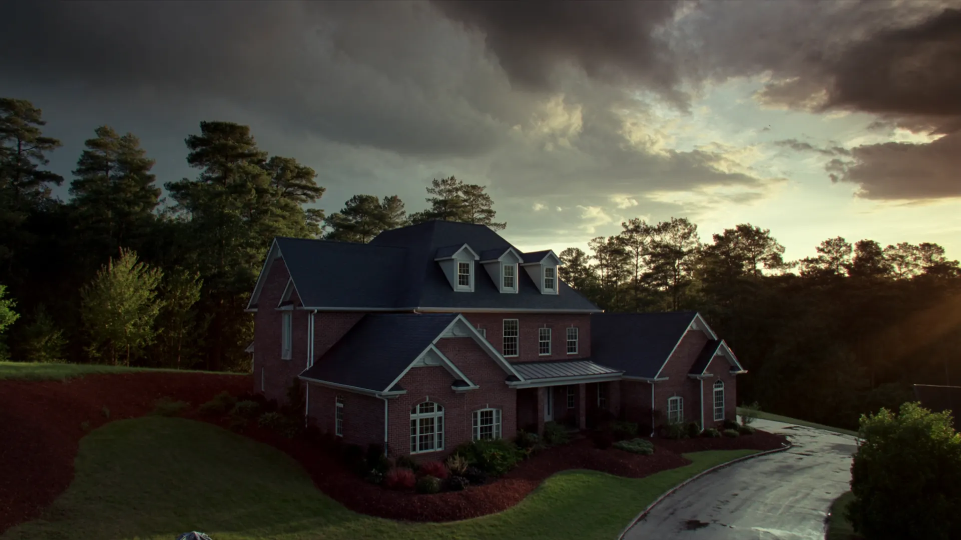 Brick home with a new architectural shingle roof under a storm sky in the Birmingham, Alabama foothills